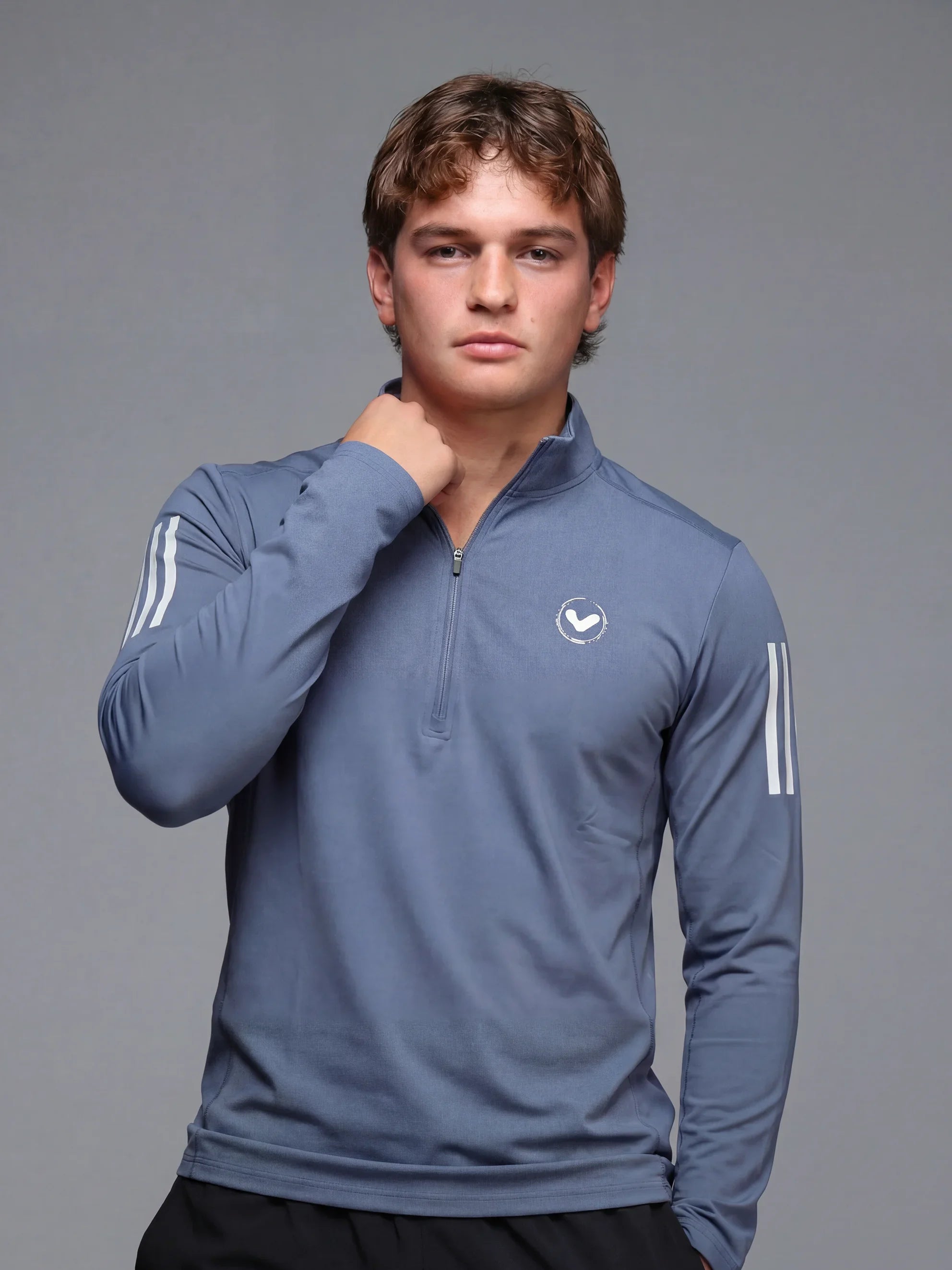 Person wearing a blue athletic jacket with a logo on a gray background