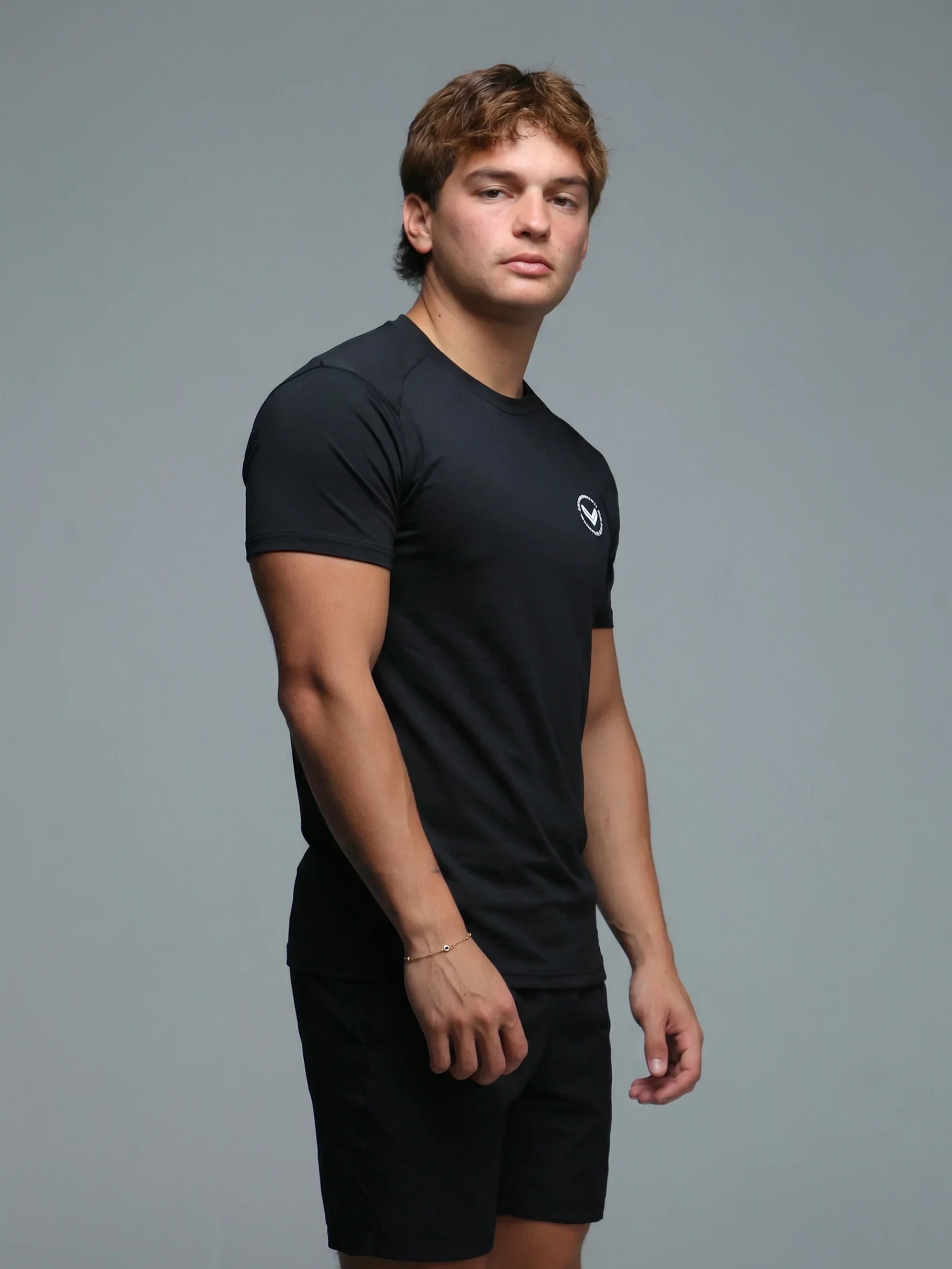 Man wearing a black t-shirt and shorts on a gray background