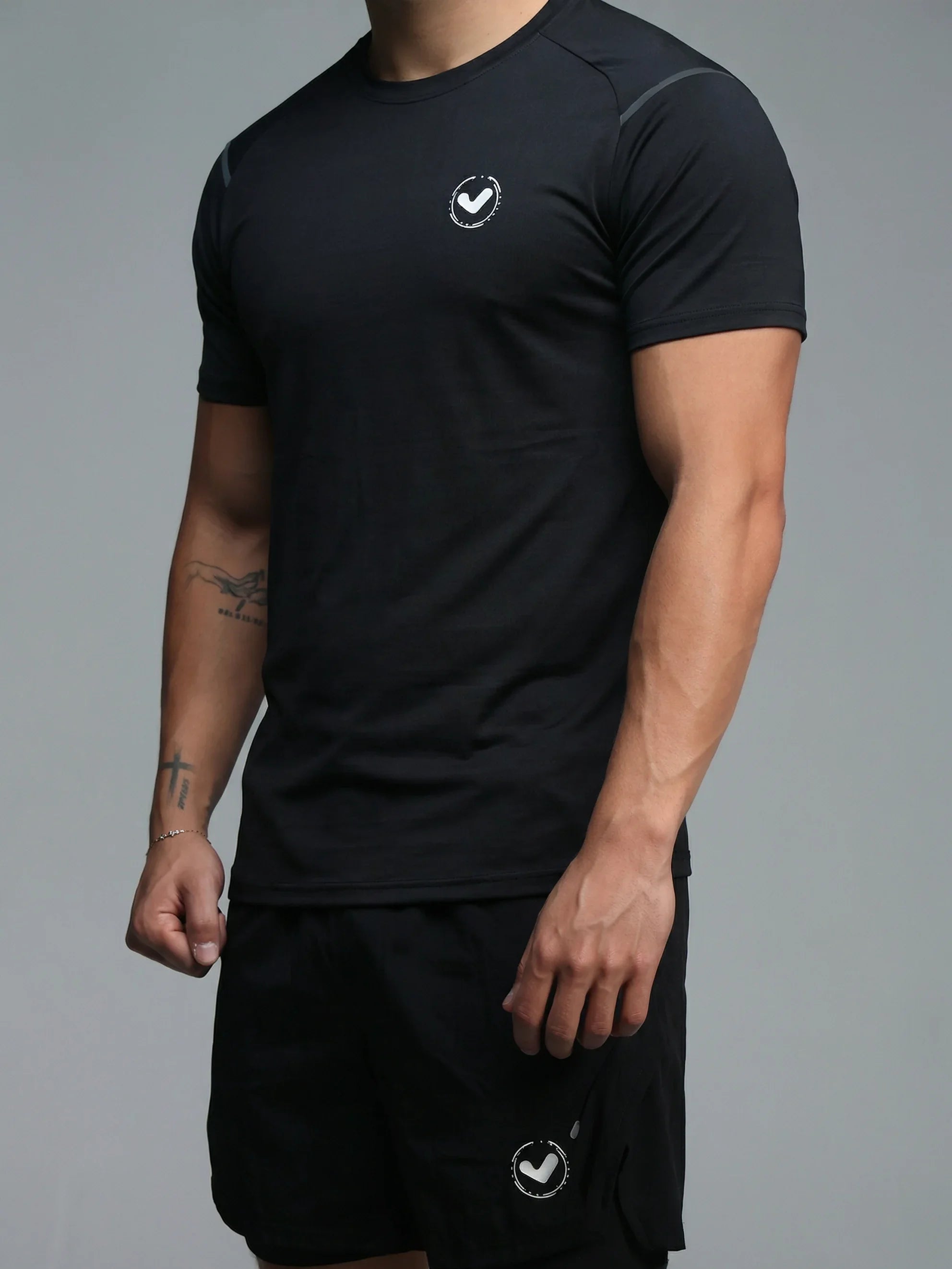 Person wearing a black athletic outfit with a logo on a gray background