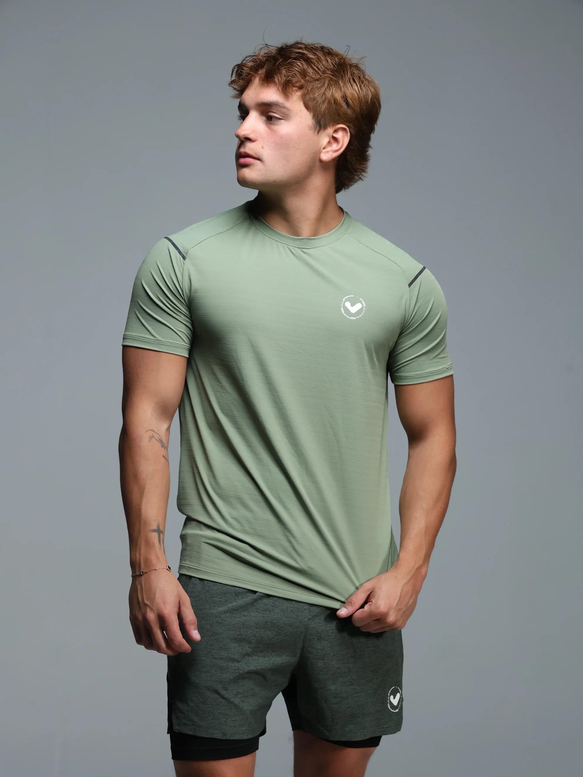 Man wearing a green athletic outfit with a logo on a gray background