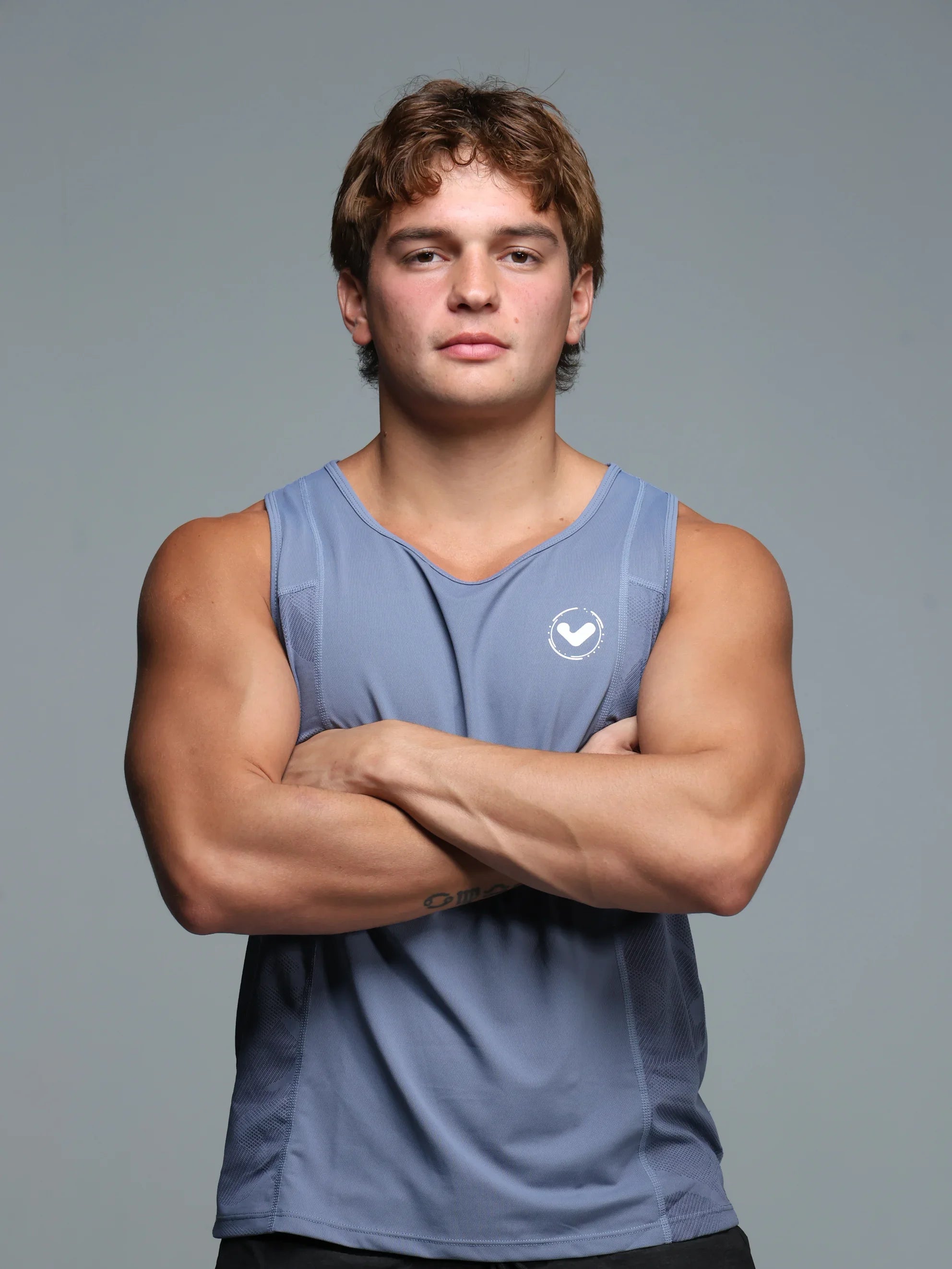 Man wearing a blue sleeveless shirt with a logo on a gray background