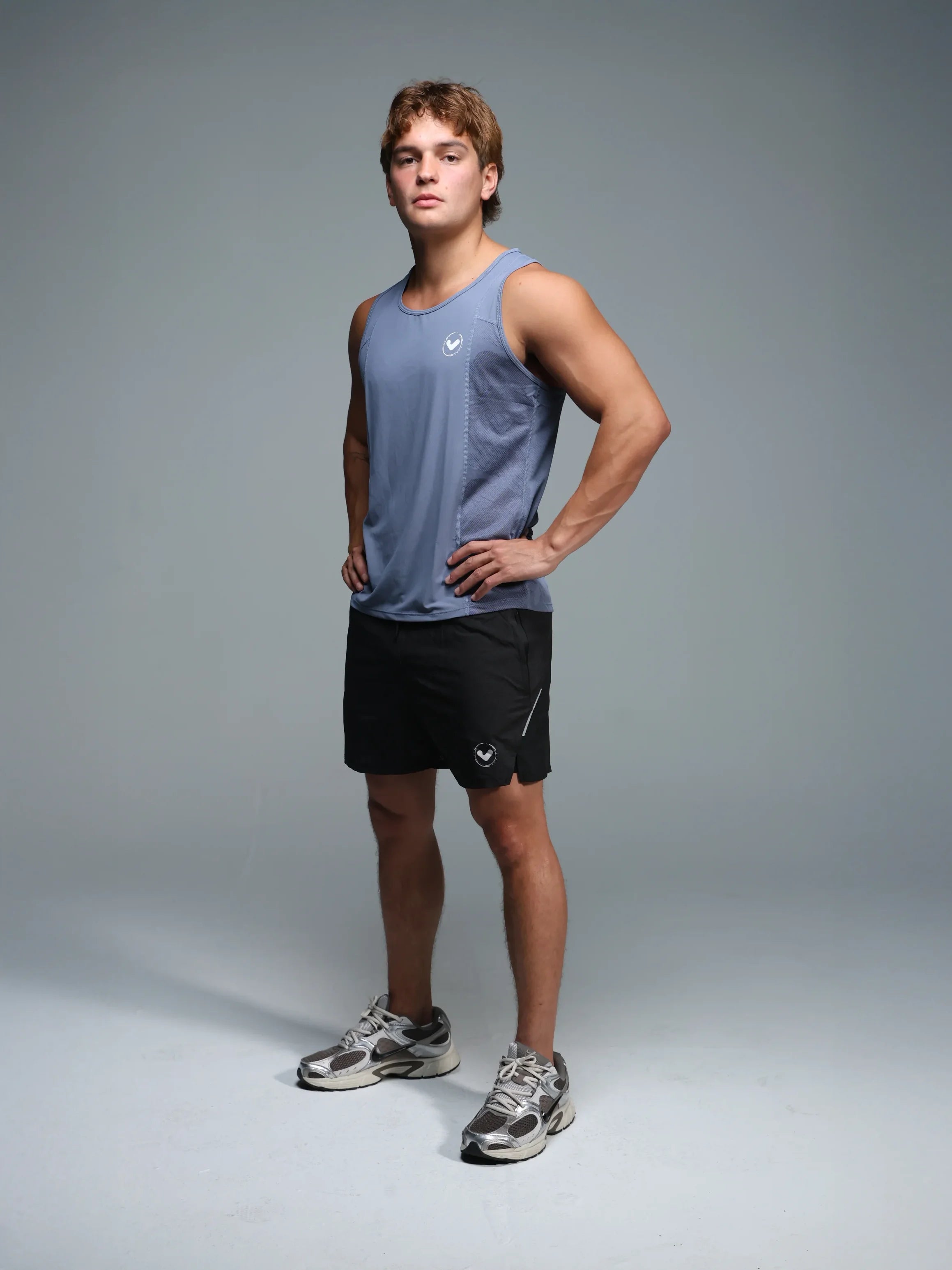 Person wearing a gray tank top and black shorts on a gray background