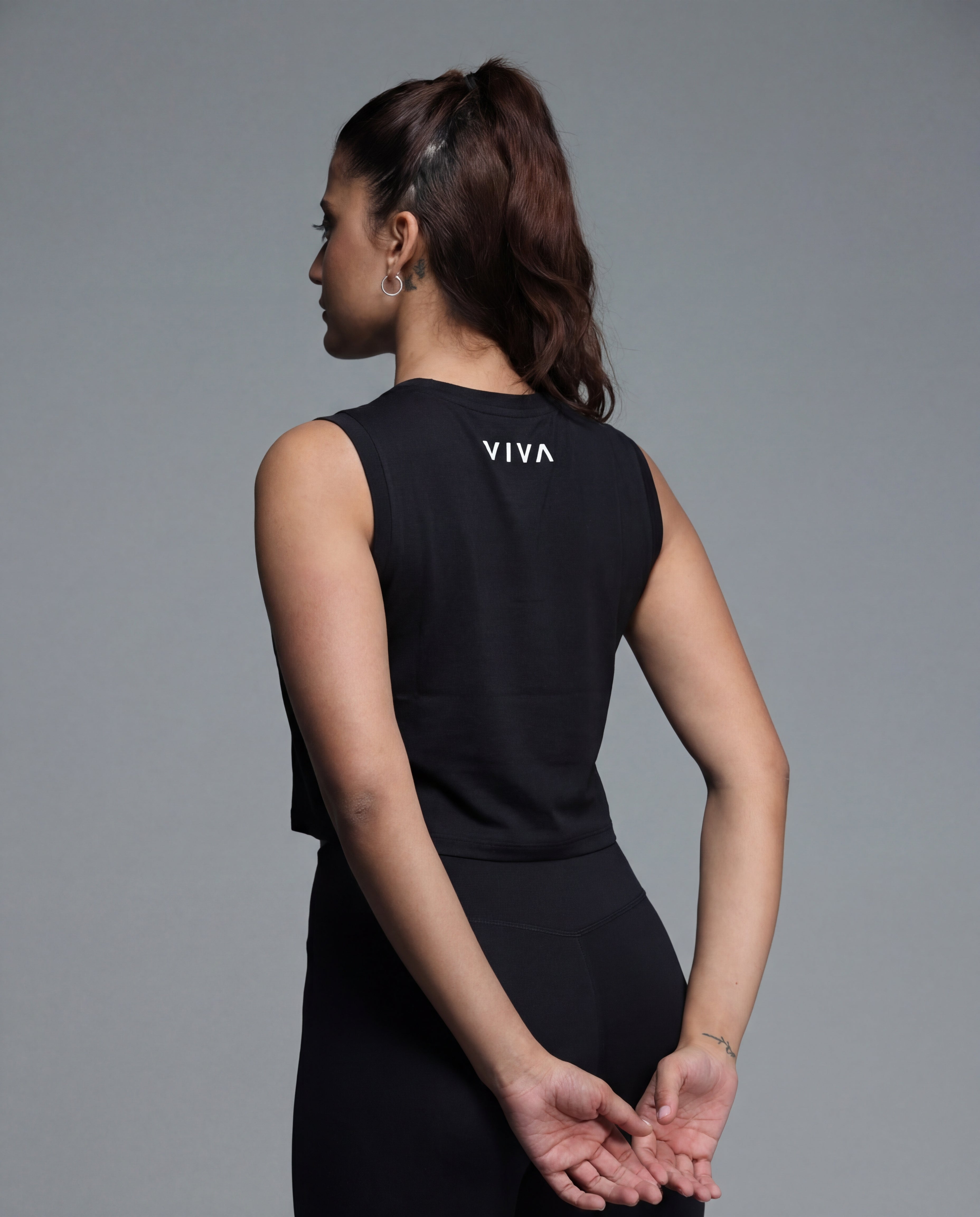 Woman wearing a black sleeveless top with 'VIVA' branding on the back against a gray background