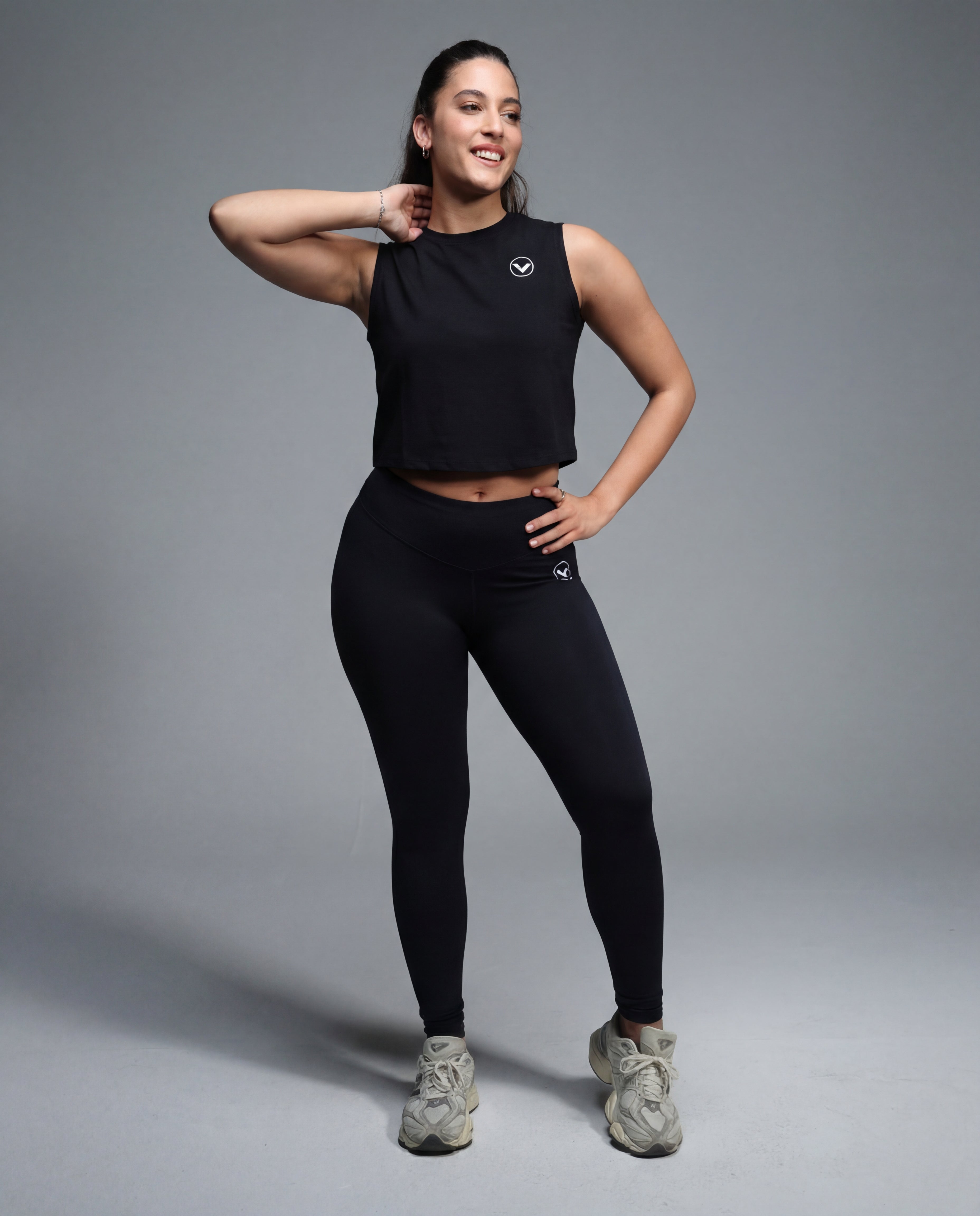 Woman wearing a black athletic outfit on a gray background