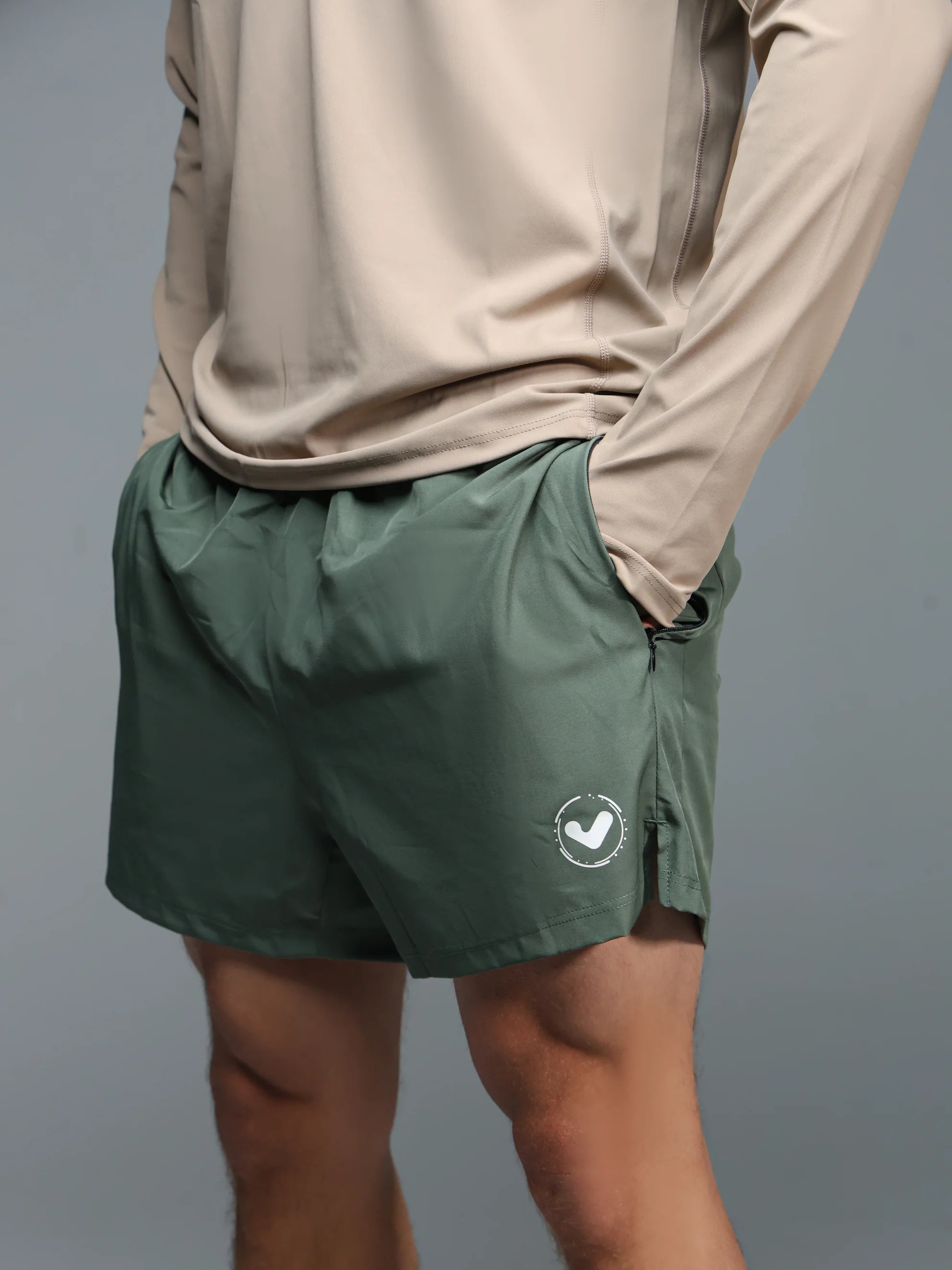 Person wearing green shorts with a logo on a gray background