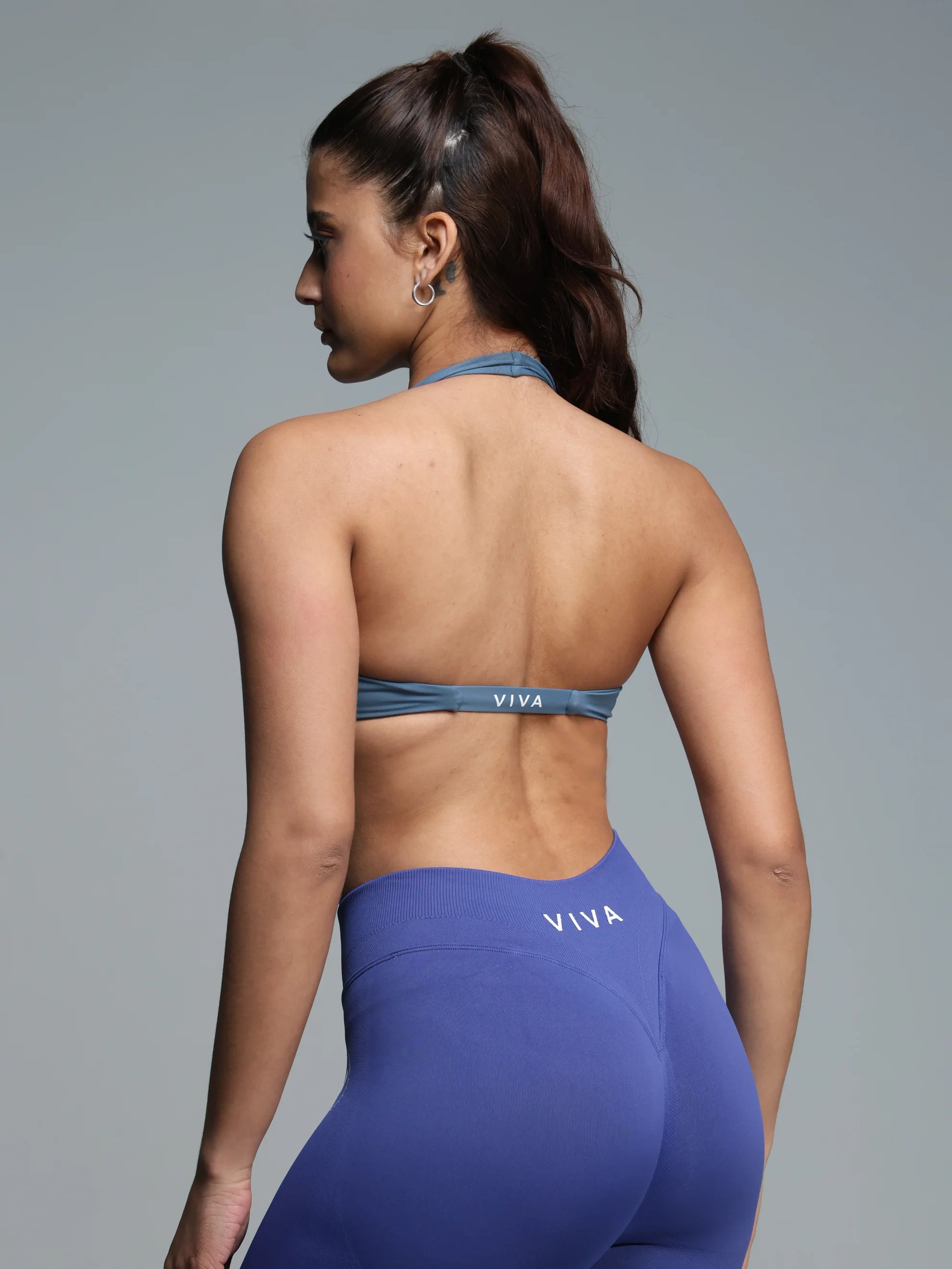 Woman wearing a blue sports bra and leggings with 'VIVA' branding on a gray background