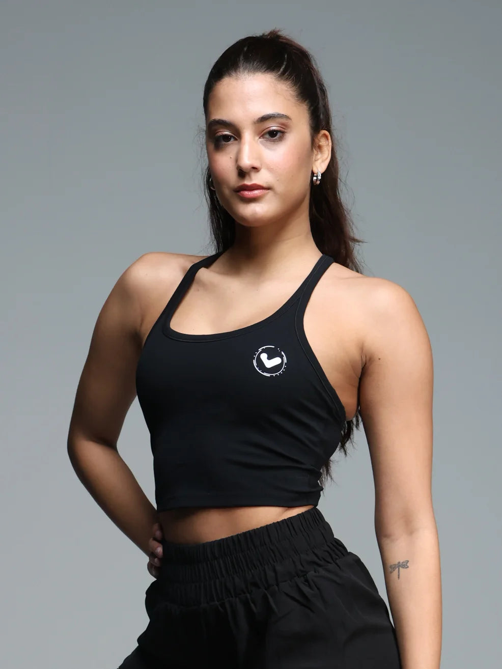 Woman wearing a black sports bra with a logo on a gray background