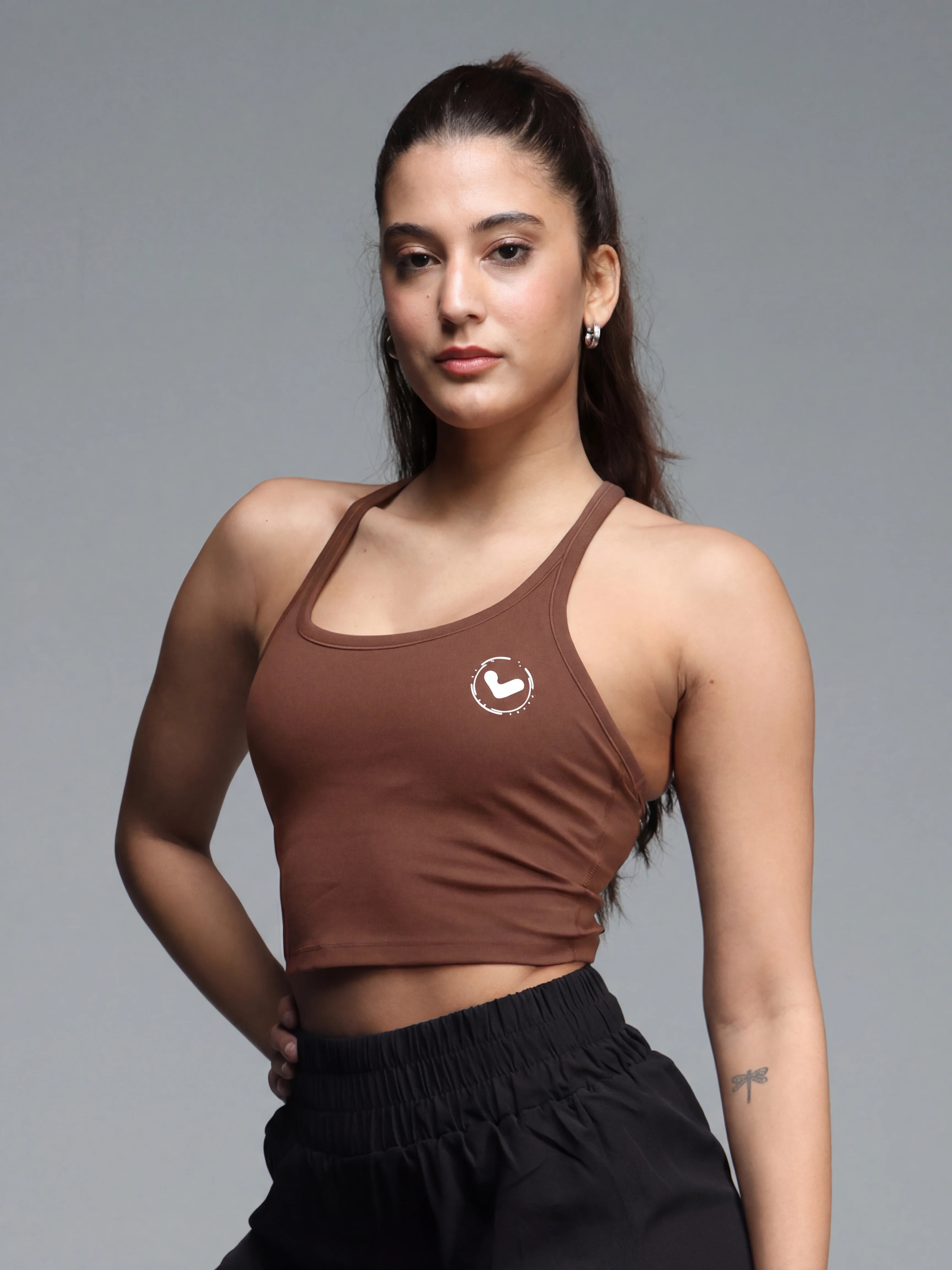 Woman wearing a brown sports bra with a logo on a gray background